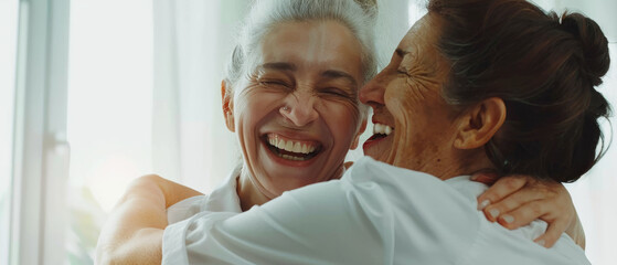 Two older women embracing warmly, sharing a joyful and heartfelt moment in a brightly lit room.