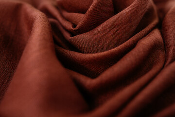 Deep, rich, orange brown colored cashmere scarf. Folded and flowing background. Decoration design. Luxury fashion concept. Dark chocolate backdrop with curves. Smooth elegant wrinkled fabric