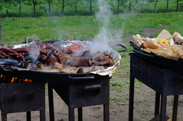 Street hot food outdoors on an open fire. Fried pig heads and various sausages