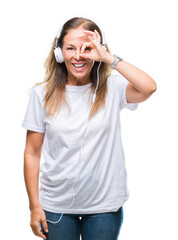 Naklejka premium Middle age hispanic woman listening to music wearing headphones over isolated background doing ok gesture with hand smiling, eye looking through fingers with happy face.