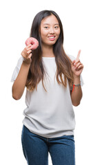 Young asian woman eating donut over isolated background surprised with an idea or question pointing finger with happy face, number one