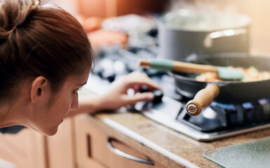 Woman, cooking and check temperature on stove in kitchen with nutrition, ingredients and heat for meal prep in home. Person, pan and pot with flame, gas and change for food, health and diet at lunch
