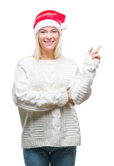 Young beautiful blonde woman wearing christmas hat over isolated background with a big smile on face, pointing with hand and finger to the side looking at the camera.