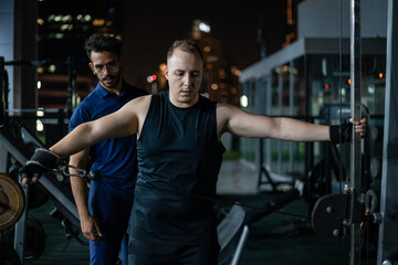 Man Working Out With Trainer at Night in Gym