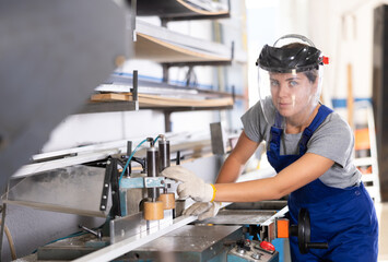 Glass workshop - girl works on a machine for cutting aluminum profiles for windows