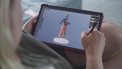 Caucasian woman creates model in 3D modeling design app using tablet computer and digital pen. Adult woman makes freelance working project lying on sofa at home. Lifestyle and remote work. Close Up.