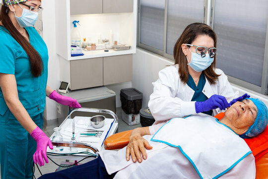 Dermatologist carrying out a skin biopsy on the face of a senior adult patient