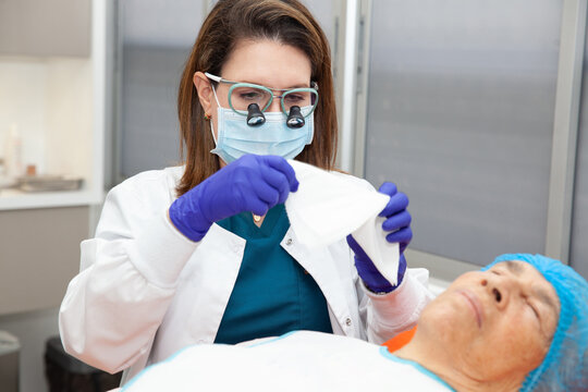 Dermatologist carrying out a skin biopsy on the face of a senior adult patient