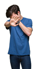 Young handsome man wearing blue t-shirt over isolated background covering eyes with hands and doing stop gesture with sad and fear expression. Embarrassed and negative concept.