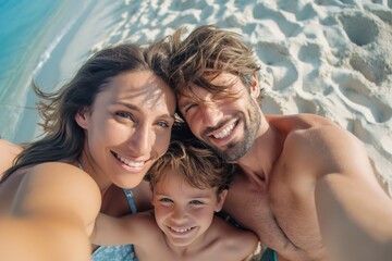 Fototapeta premium Family of three smiles for a selfie on a sandy beach. The father is shirtless, and the mother and son are both wearing swimwear