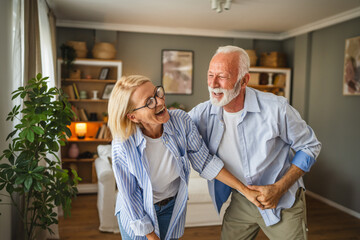 Senior active couple husband and wife dance and enjoy together at home