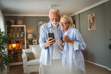 Senior couple husband and wife use mobile phone together at home