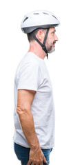 Middle age senior hoary cyclist man wearing bike safety helment isolated background looking to side, relax profile pose with natural face with confident smile.