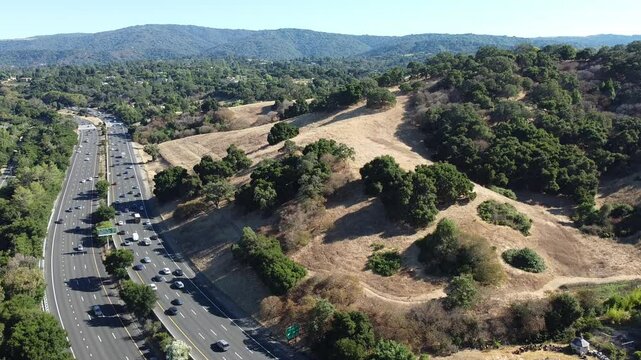 Aerial view of a busy highway 280 winding through a scenic landscape of hills and trees near Los Altos Hills, California