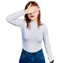 Fototapeta premium Redhead young woman wearing casual turtleneck sweater covering eyes with hand, looking serious and sad. sightless, hiding and rejection concept