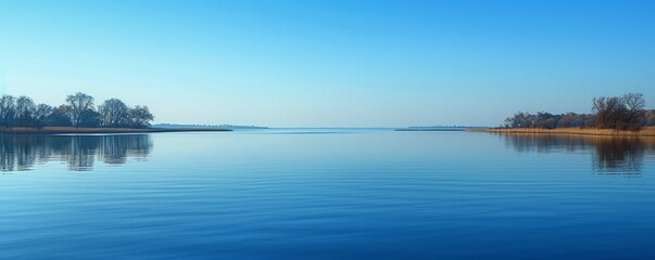 A calm, reflective lake mirroring a clear blue sky.