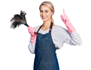 Beautiful young blonde woman wearing apron holding cleaning duster pointing finger up with successful idea. exited and happy. number one.