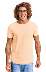 Young hispanic man wearing casual clothes and glasses winking looking at the camera with sexy...