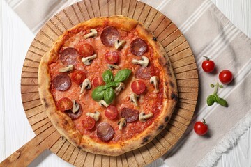 Delicious pizza with tomatoes, salami, mushrooms and basil on white wooden table, top view