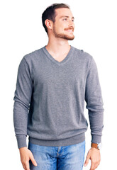 Fototapeta premium Young handsome caucasian man wearing casual winter sweater looking away to side with smile on face, natural expression. laughing confident.