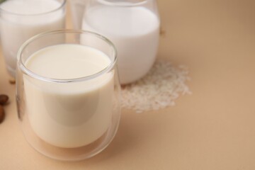 Different types of vegan milk and ingredients on beige table, closeup