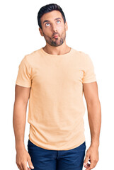 Fototapeta premium Young hispanic man wearing casual clothes making fish face with lips, crazy and comical gesture. funny expression.