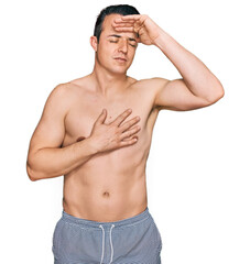 Fototapeta premium Handsome young man wearing swimwear shirtless touching forehead for illness and fever, flu and cold, virus sick