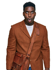 Handsome business black man wearing leather bag scared and amazed with open mouth for surprise, disbelief face