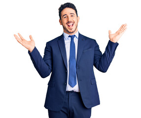 Young hispanic man wearing business clothes celebrating victory with happy smile and winner expression with raised hands