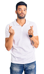 Young handsome hispanic man wearing casual clothes doing money gesture with hands, asking for salary payment, millionaire business