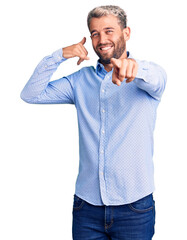 Young handsome blond man wearing elegant shirt smiling doing talking on the telephone gesture and...