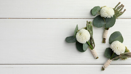 Small stylish boutonnieres on white wooden table, flat lay. Space for text © New Africa