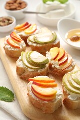 Delicious ricotta bruschettas with pears and apricots on white table, closeup