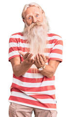 Old senior man with grey hair and long beard wearing striped tshirt smiling with hands palms together receiving or giving gesture. hold and protection