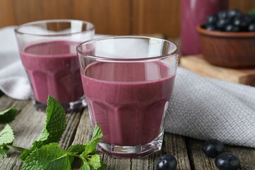 Tasty fresh acai juice in glasses with berries and mint on wooden table, closeup
