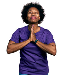 African american woman with afro hair wearing casual purple t shirt praying with hands together...