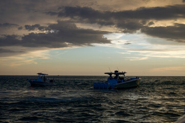 Obraz premium Sunset cruise views from the boat. Other boats seen on the horizon as the sun is setting 