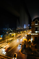 Night view of Baku from a hotel window with a tilt-shift effect showcasing fast-moving cars on the...
