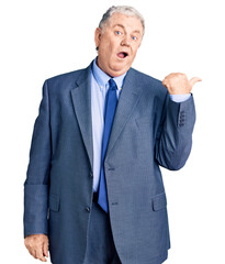 Senior grey-haired man wearing business jacket surprised pointing with hand finger to the side, open mouth amazed expression.