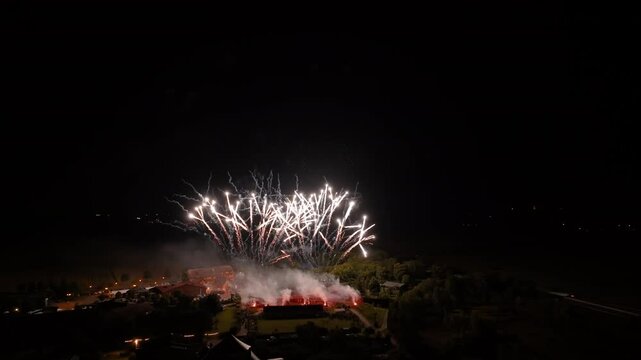 Spectaculaire feu d'artifice illuminant le ciel nocturne avec des &eacute;clats dor&eacute;s et des explosions &eacute;tincelantes, captur&eacute; au-dessus d'une petite ville.