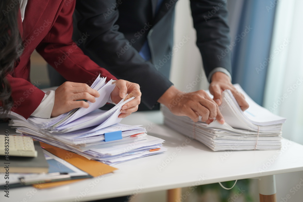 Wall mural Two accountants working with piles of documents in office business finance and accounting concepts Businessman picks up overloaded documents Try to organize and categorize documents in your office.