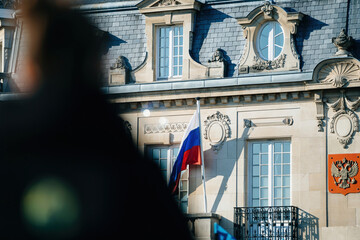A Russian flag and the national coat of arms featuring a two-headed bird wave on the consulate in...