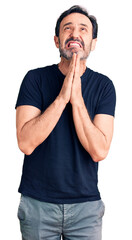 Middle age handsome man wearing casual t-shirt begging and praying with hands together with hope expression on face very emotional and worried. begging.