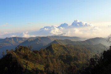 Beautiful scenery of hill formations and clouds in the distance under a blue sky in the afternoon