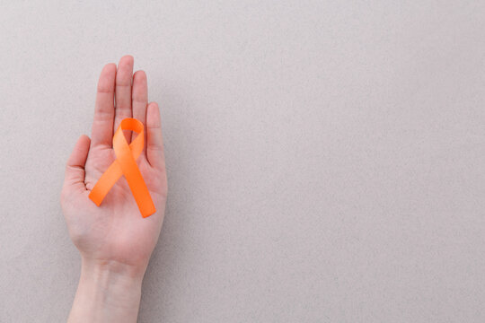 Woman with orange awareness ribbon on gray background, top view. Space for text