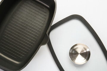 Black pot and glass lid on white background, top view