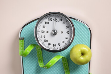 Scale, measuring tape and fresh apple on beige background, top view