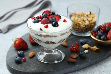 Tasty yogurt with fresh berries, granola and nuts on gray table, closeup