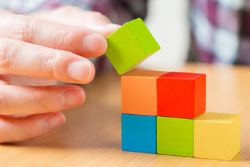 階段状に積み木を積む人の手元