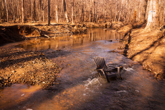 A plastic chair sits in the middle of a stream in a forest in Durham, North Carolina